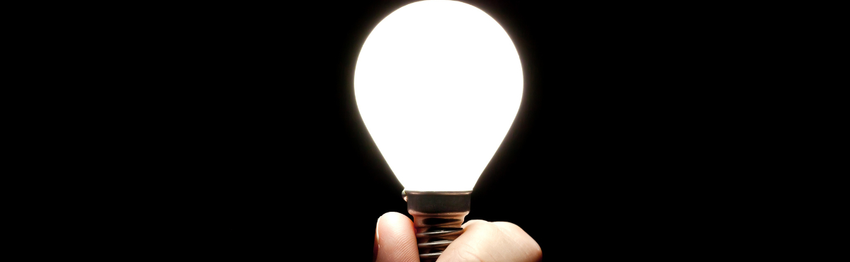 Hand holding up a white globe in front of a black background.