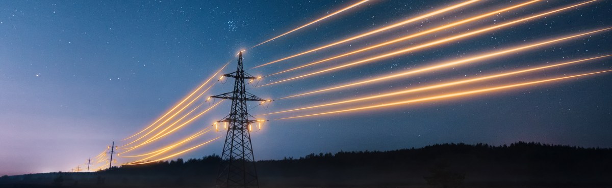 Powerlines with glowing yellow light along dark blue sky.