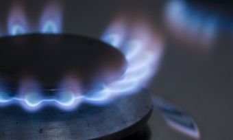 Gas stove top turned on with blue flame.