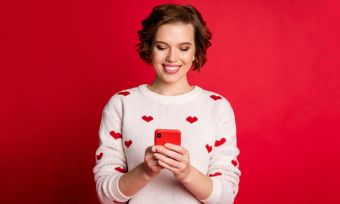 Young woman with red smartphone on red background