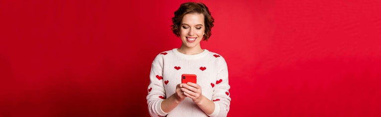 Young woman with red smartphone on red background