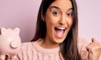 Woman happy, dressed in pink, holding piggy bank.