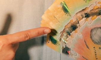 Man holding wad of $50 notes and pointing to it.