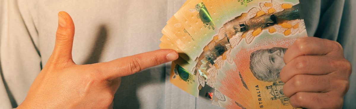 Man holding wad of $50 notes and pointing to it.