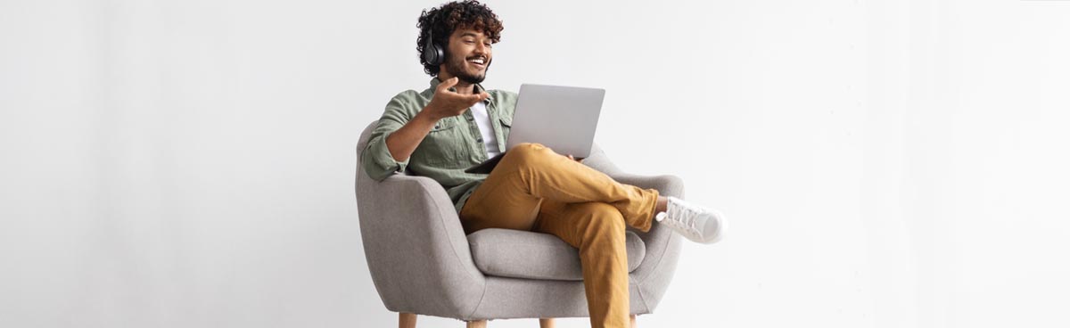 Smiling man using laptop with headphones