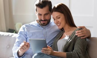 Man and woman looking at tablet device on sofa