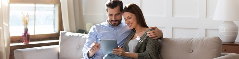 Man and woman looking at tablet device on sofa