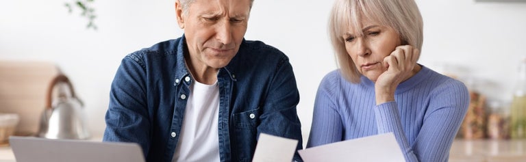 Older couple lookin at bills together, confused.
