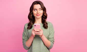 Woman holding phone against pink background