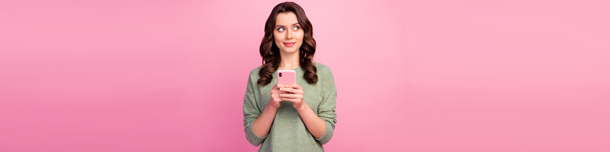 Woman holding phone against pink background