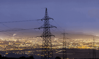 Power grid in the early evening, with city lights in the background.