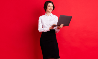 Smiling woman using laptop with red background
