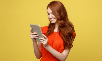 Smiling young girl using tablet with orange background
