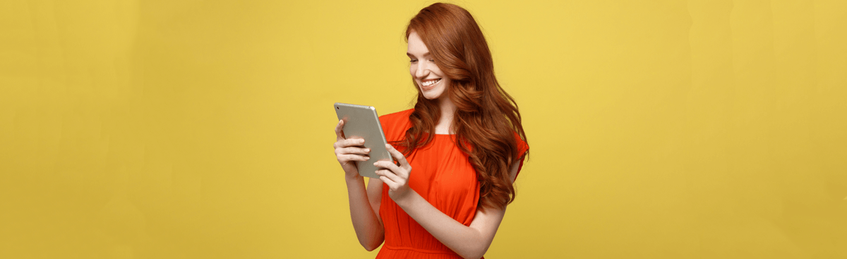 Smiling young girl using tablet with orange background