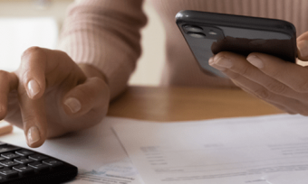 Person holding phone and using calculator