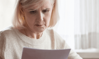 Older woman looking concerned at energy bill.