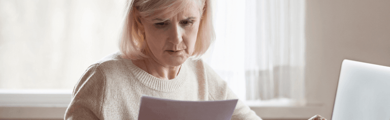 Older woman looking concerned at energy bill.