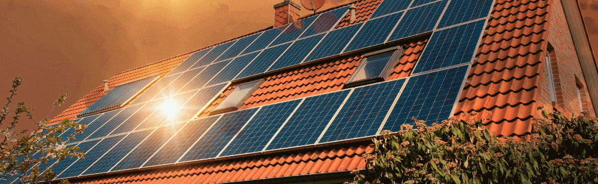 Solar panels on a rooftop with sunlight reflecting off of them.