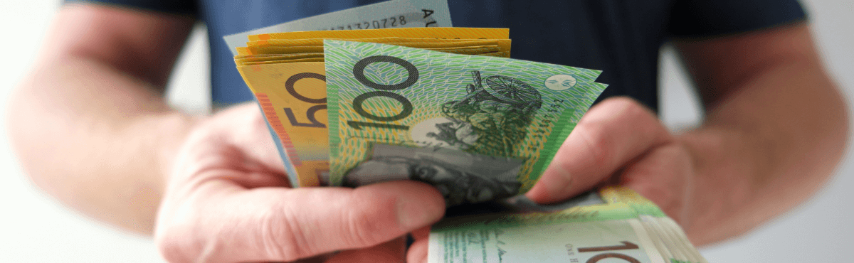 Man holding handful of Australian cash notes.