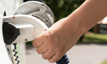Hand holding EV charger to car.