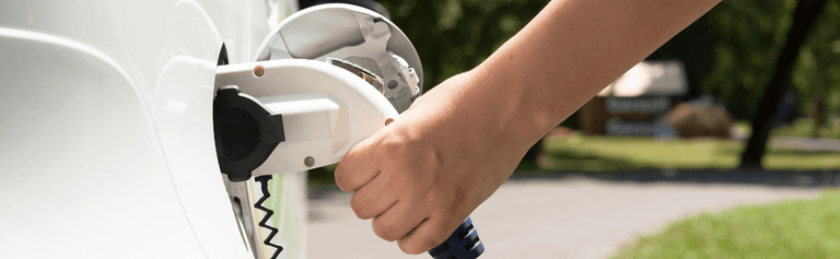 Hand holding EV charger to car.