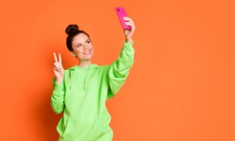Woman taking selfie against orange background