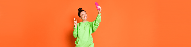 Woman taking selfie against orange background