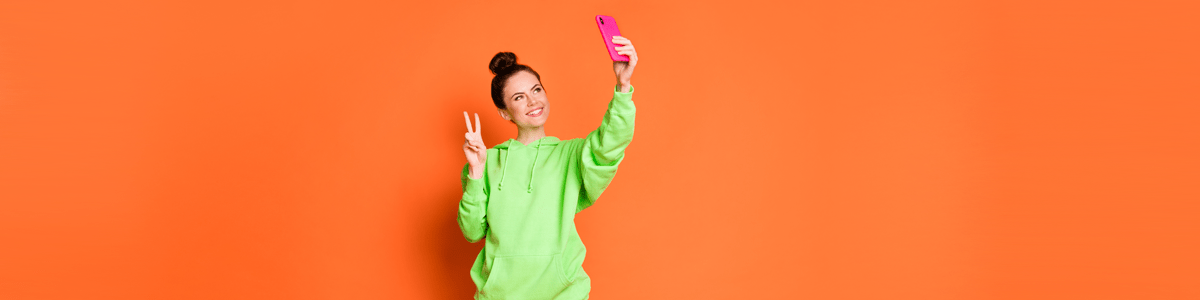 Woman taking selfie against orange background