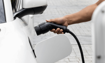 Man charging white electric vehicle from home.