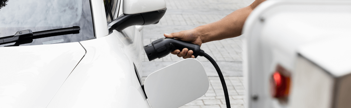 Man charging white electric vehicle from home.