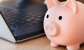 Pink piggy bank next to laptop