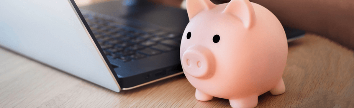 Pink piggy bank next to laptop