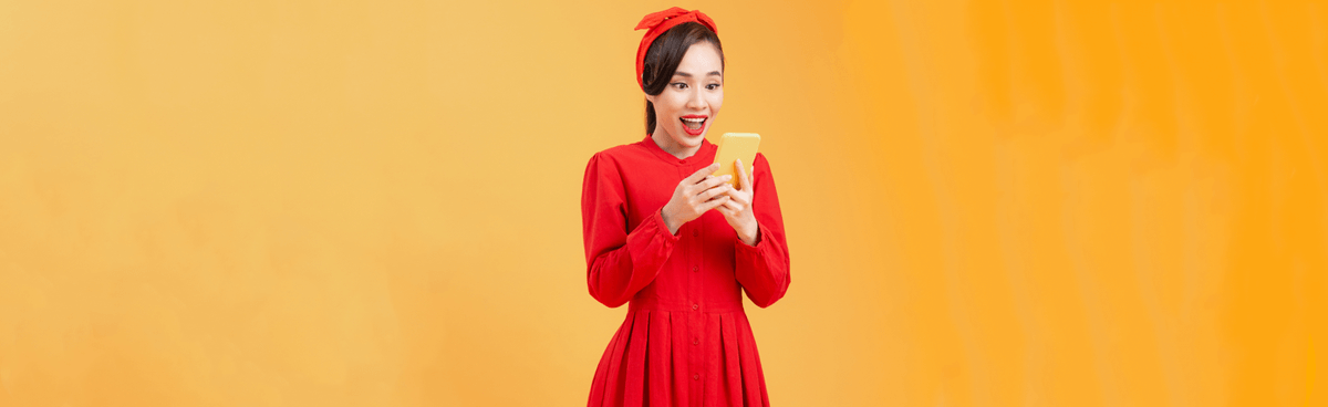 Young surprised woman in red looking at phone