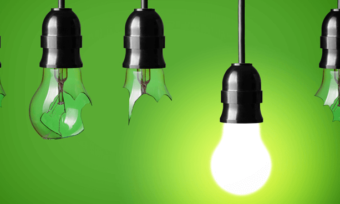 Broken and working lightbulbs hanging with green background