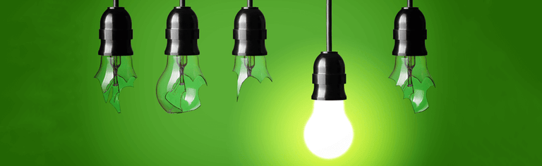 Broken and working lightbulbs hanging with green background