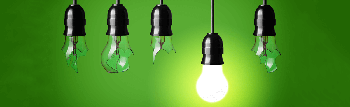 Broken and working lightbulbs hanging with green background