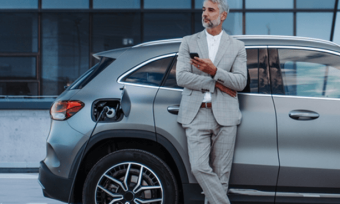 Businessman charging silver electric vehicle