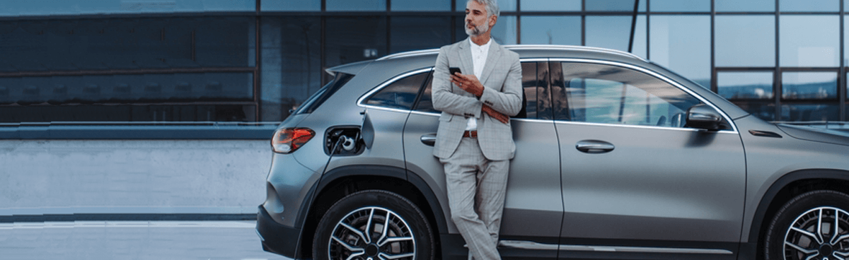 Businessman charging silver electric vehicle