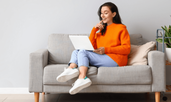 Happy woman using laptop on couch