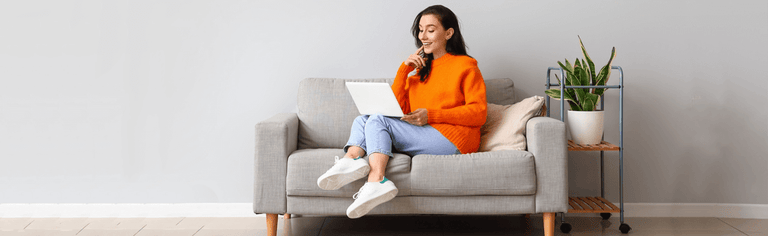 Happy woman using laptop on couch