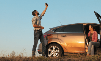 Man and woman looking for mobile signal on country road