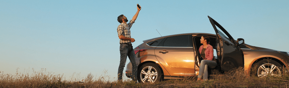 Man and woman looking for mobile signal on country road