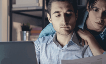 Couple looking somberly at bill in front of computer.