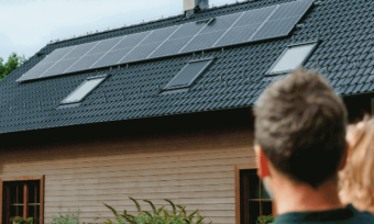 Father and daughter looking at solar panels on rooftop.