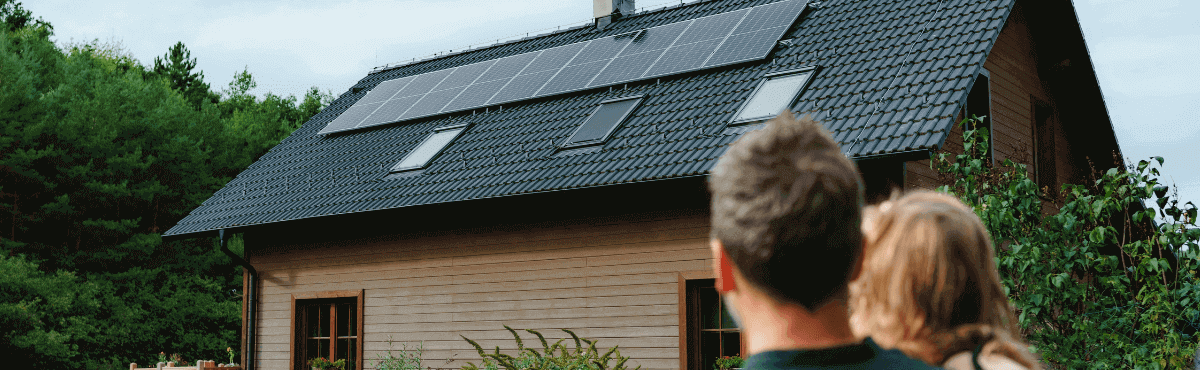 Father and daughter looking at solar panels on rooftop.