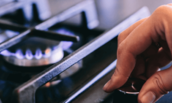 Hand turning dial on a gas stovetop.