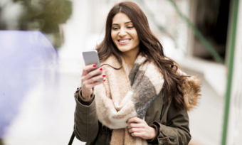 Smiling woman using smartphone outdoors in cold weather