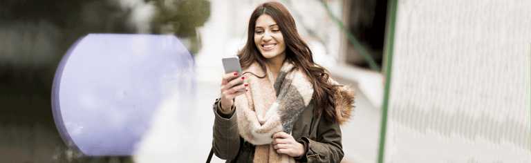 Smiling woman using smartphone outdoors in cold weather