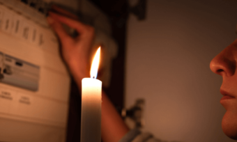 Woman looking at electricity meter with candle.