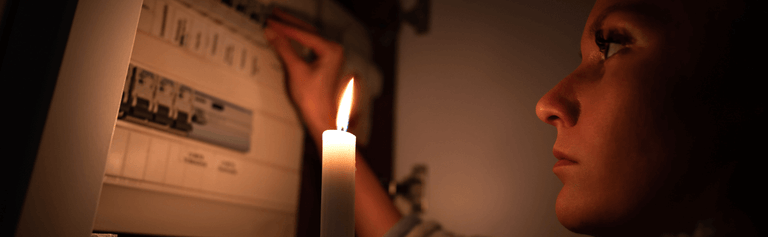 Woman looking at electricity meter with candle.